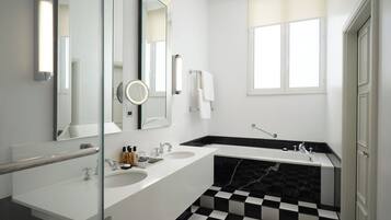 Un baño moderno con un espejo grande, dos lavamanos, una bañera y un suelo a cuadros.