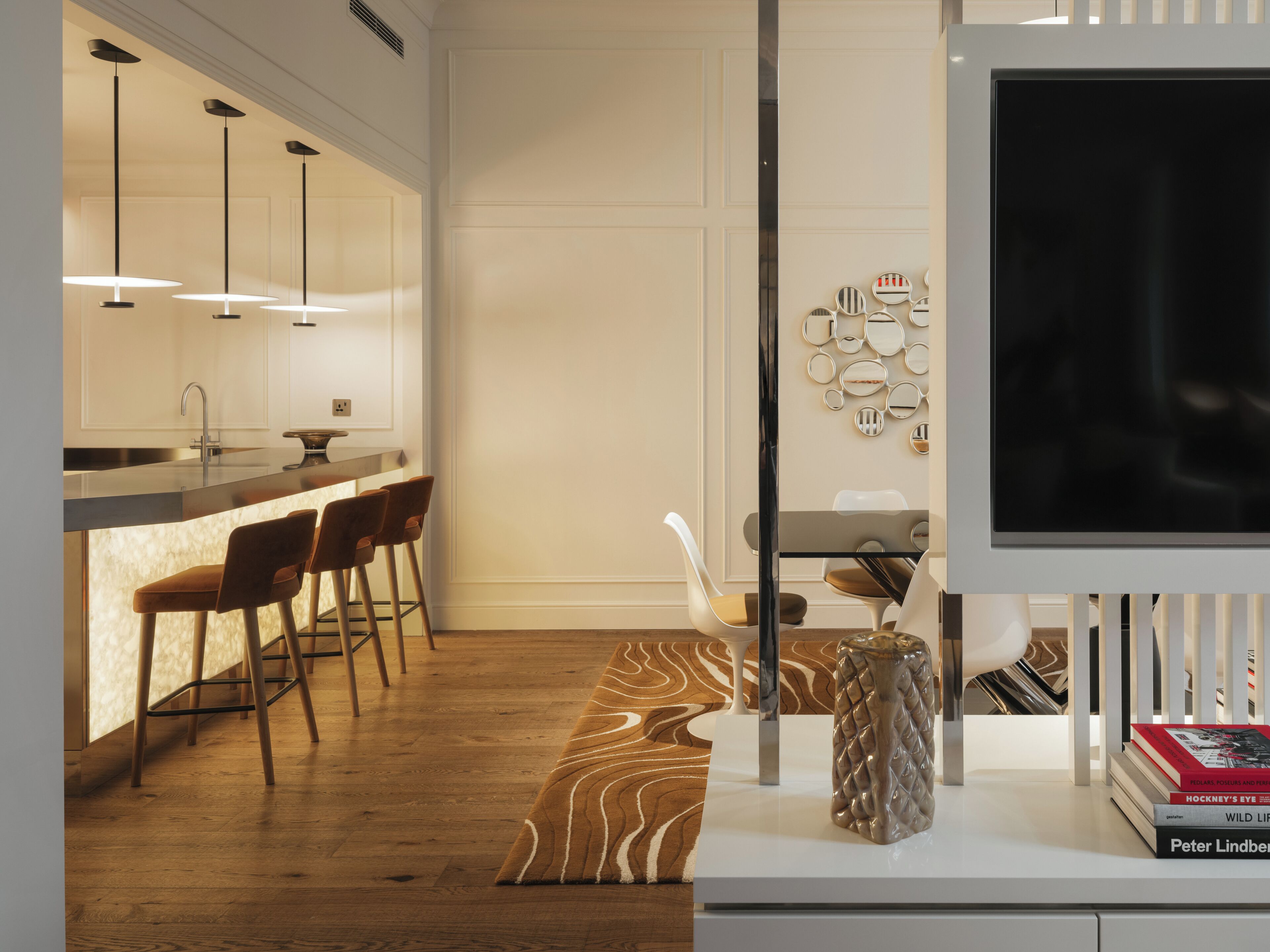 Eine moderne Küche mit Bar, Holzboden und einem Flachbildfernseher auf einem Standfuß.