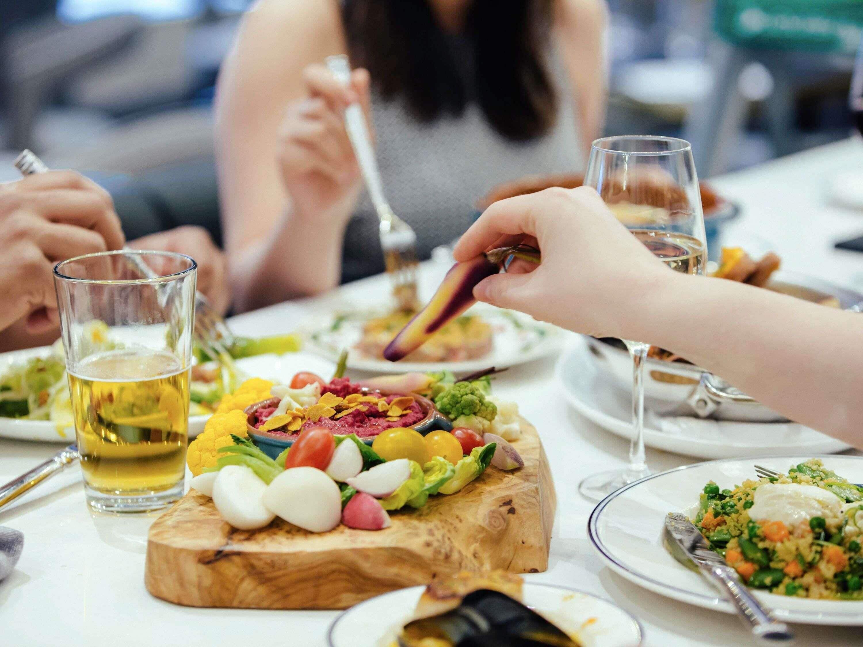 Une table à manger avec différents plats, couverts et verres.