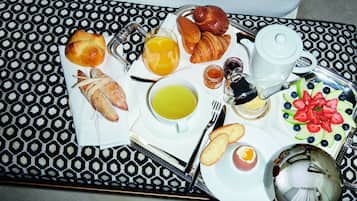 A breakfast tray with croissants, bread, fruit, and beverages.