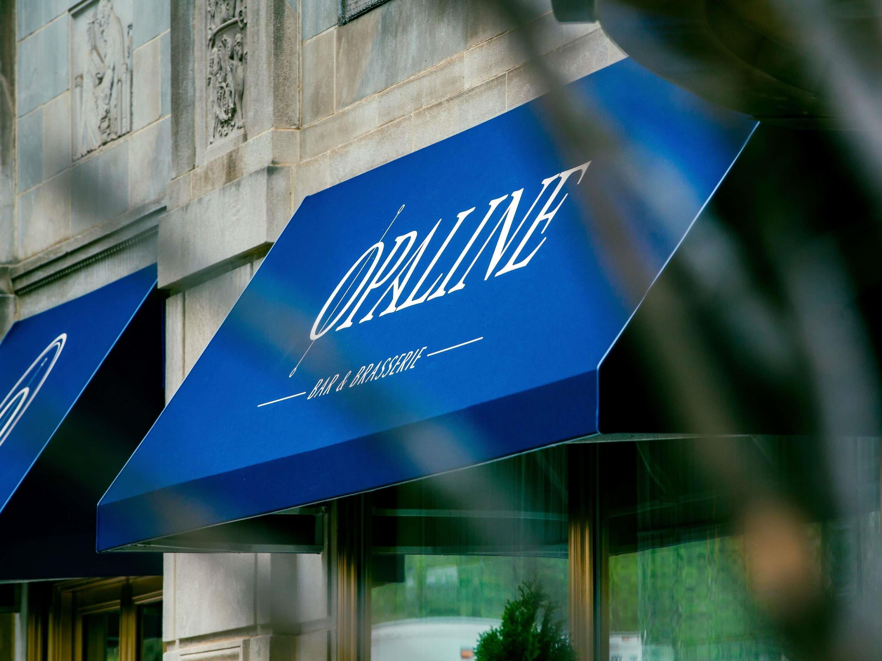 A building with a blue awning displaying the word 'OPALINE' and the phrase 'BAR & BRASSERIE' underneath.