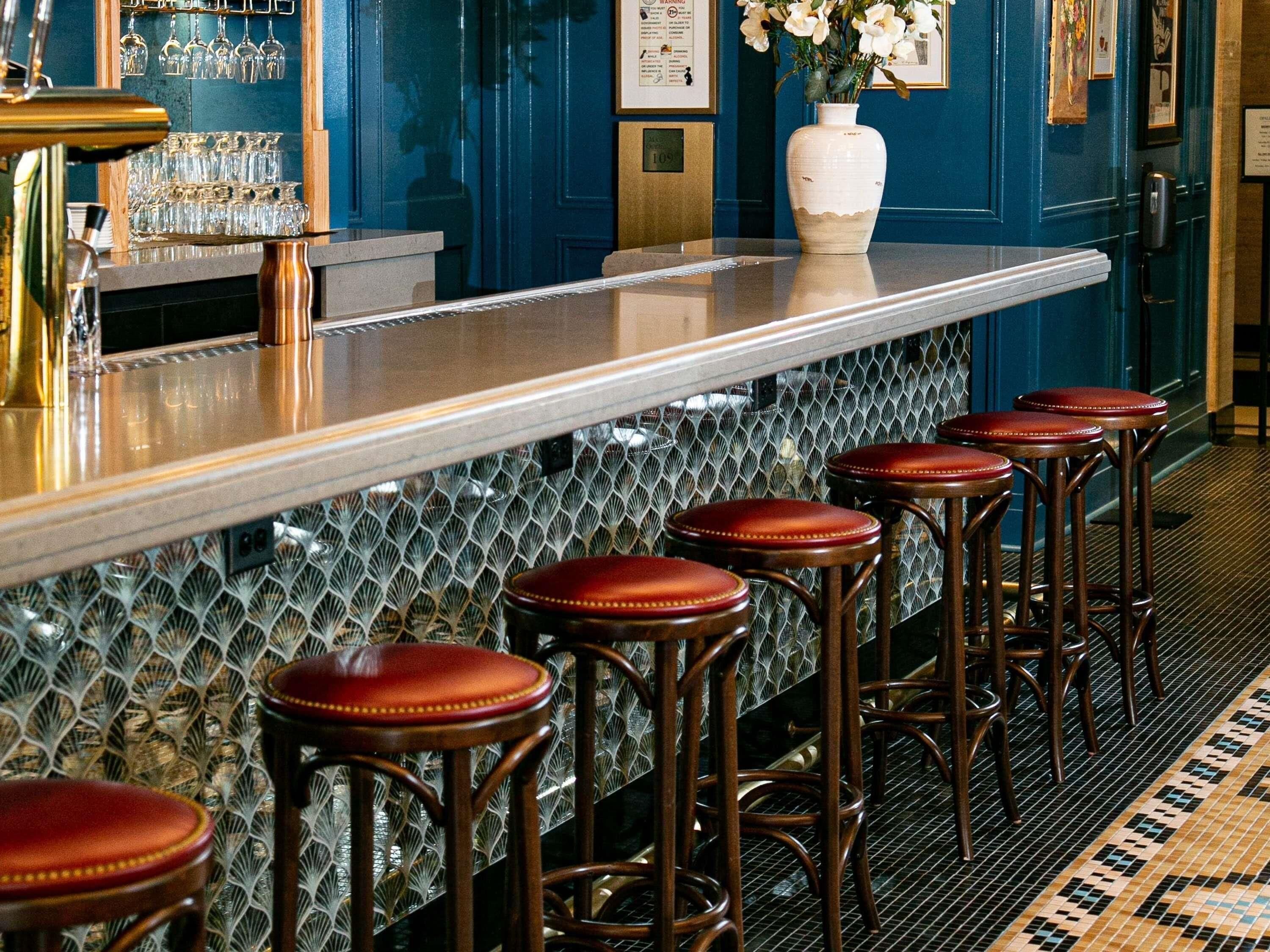 Un área de bar con taburetes, una barra y una pared decorativa con un diseño geométrico.