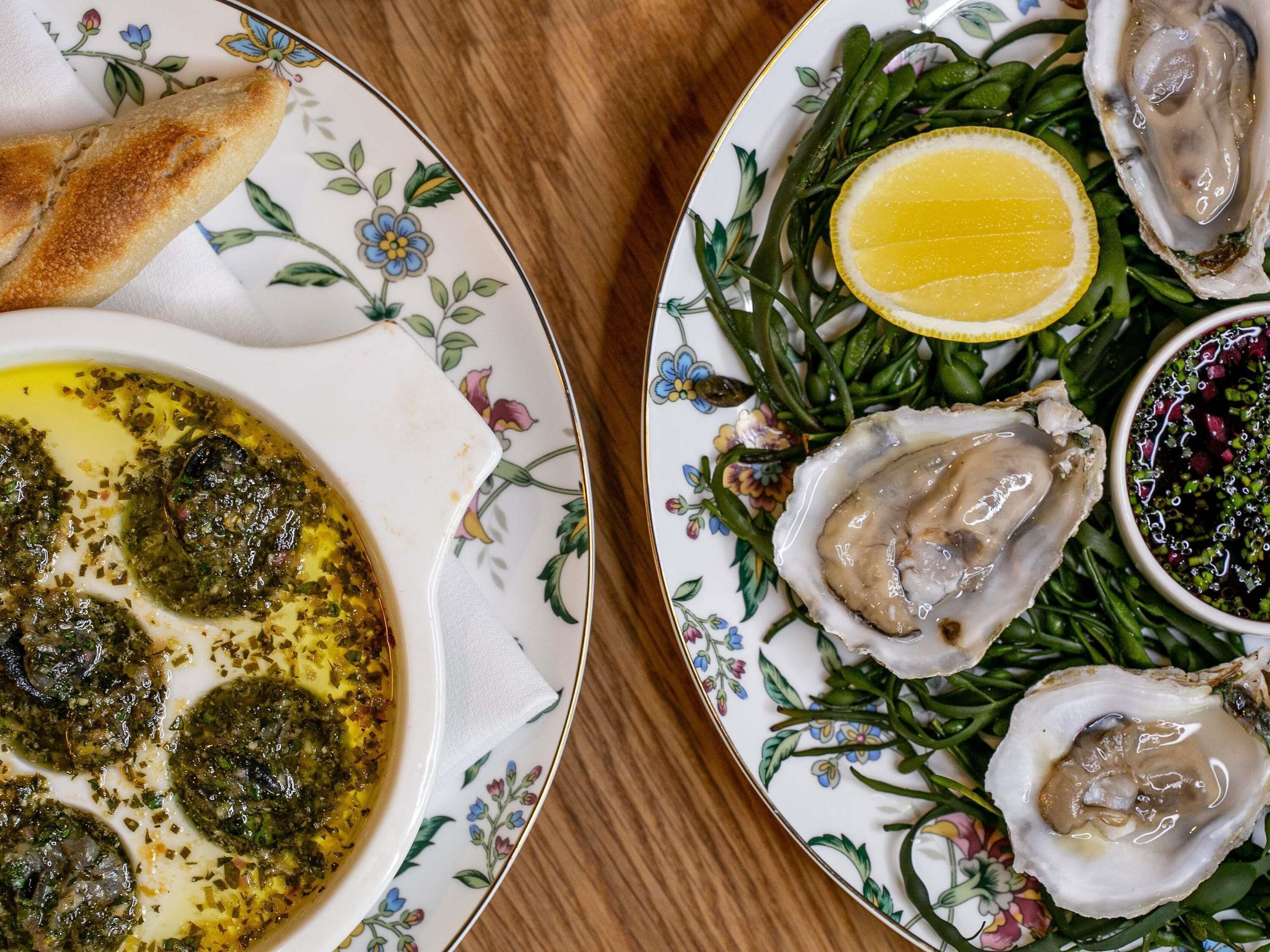 Een bord met oesters, groen en een partje citroen.