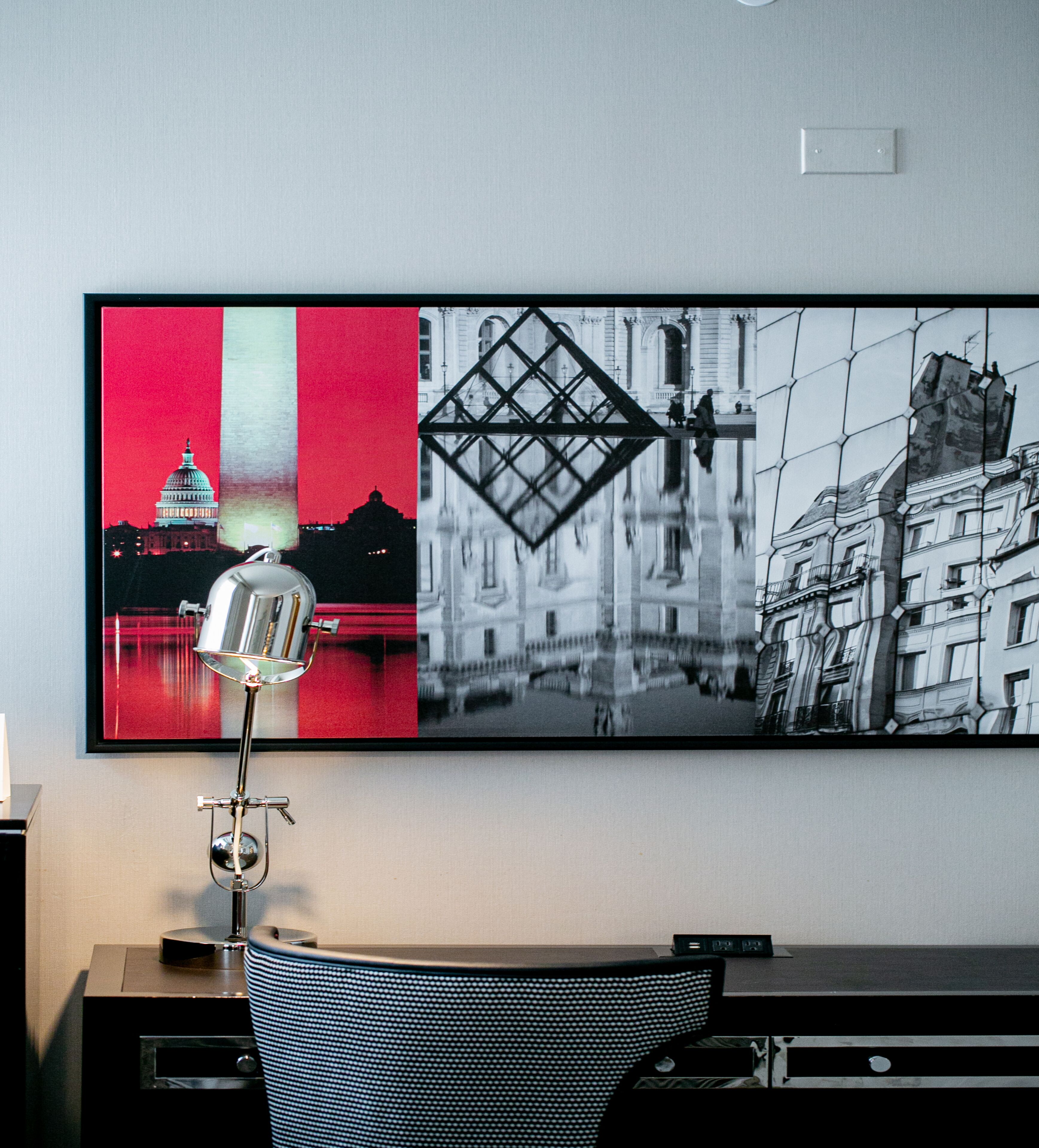 Una habitación moderna con escritorio, silla y una obra de arte grande enmarcada en la pared.