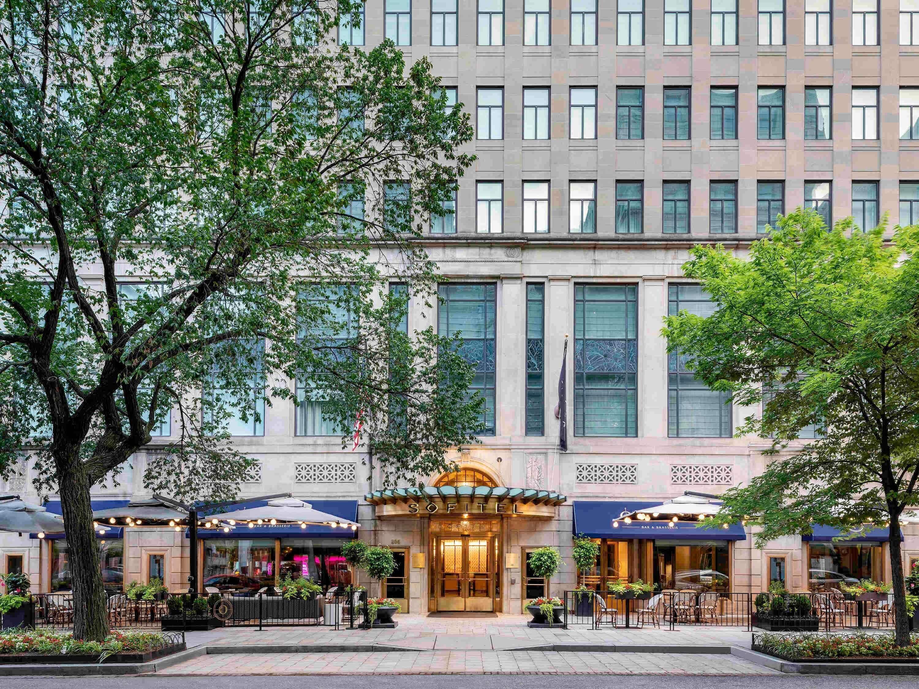 A hotel with a classic facade, large windows, and outdoor seating areas.