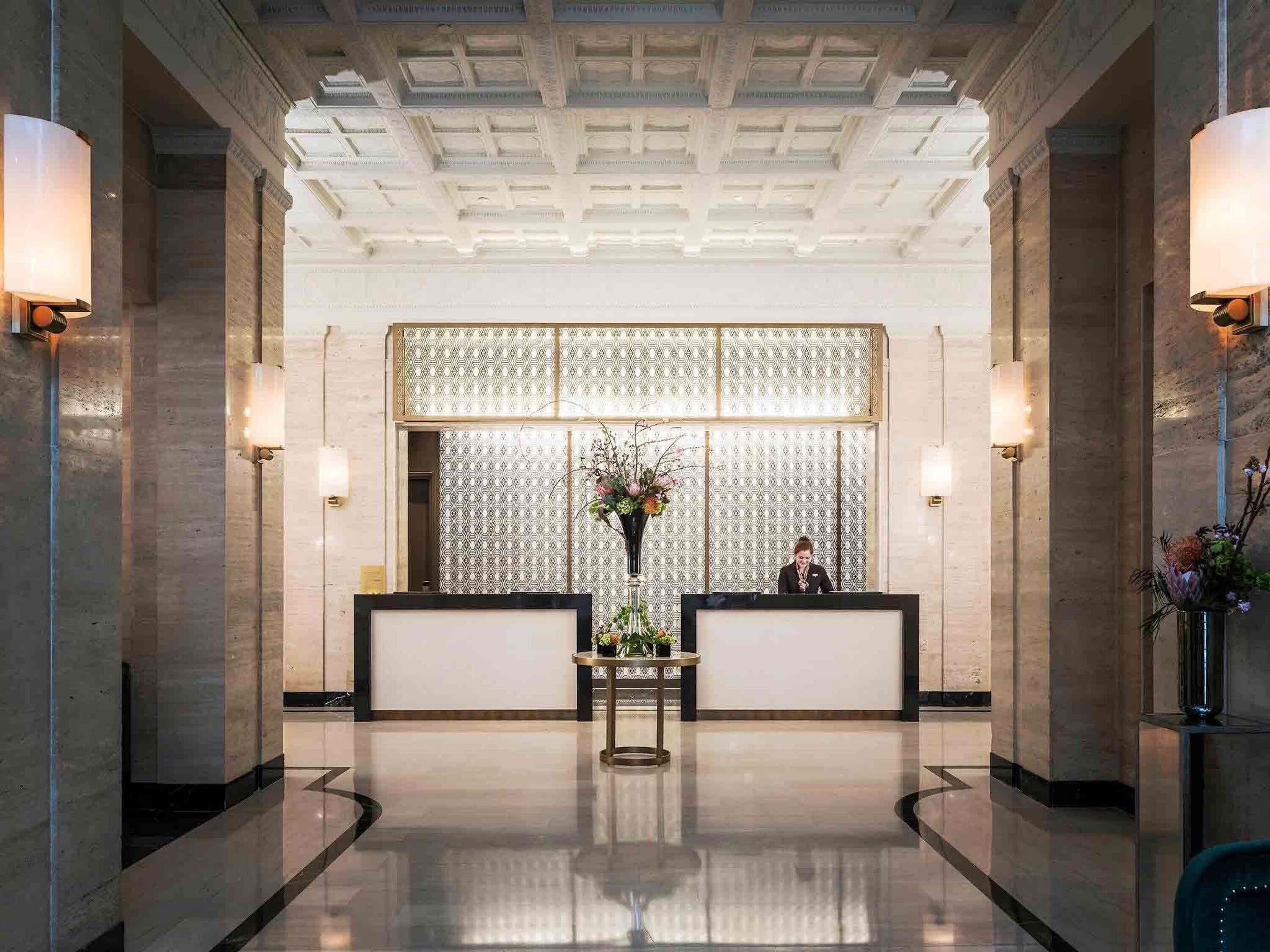 Una hall con una reception, un muro decorato e un soffitto a griglia.
