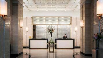 A lobby with a reception desk, a patterned wall, and a ceiling with a grid design.