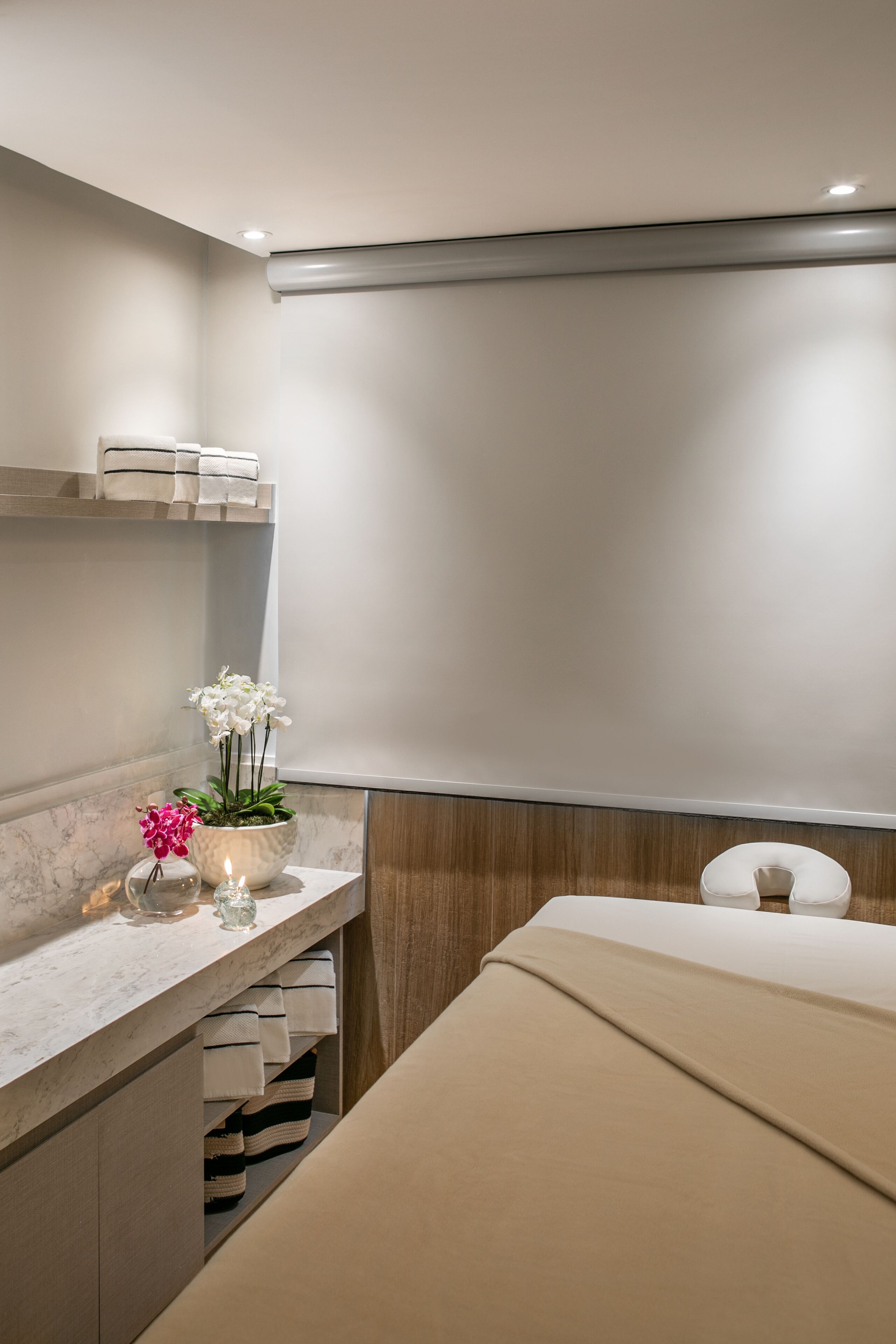 A modern bathroom with a marble countertop, a sink, a white orchid, and a beige towel.