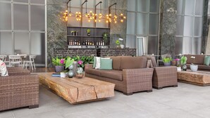 A modern outdoor seating area with wicker furniture, a wooden coffee table, and a wall-mounted light fixture.