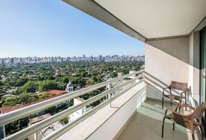 Un balcon avec vue sur la ville, des fauteuils en osier et une balustrade.