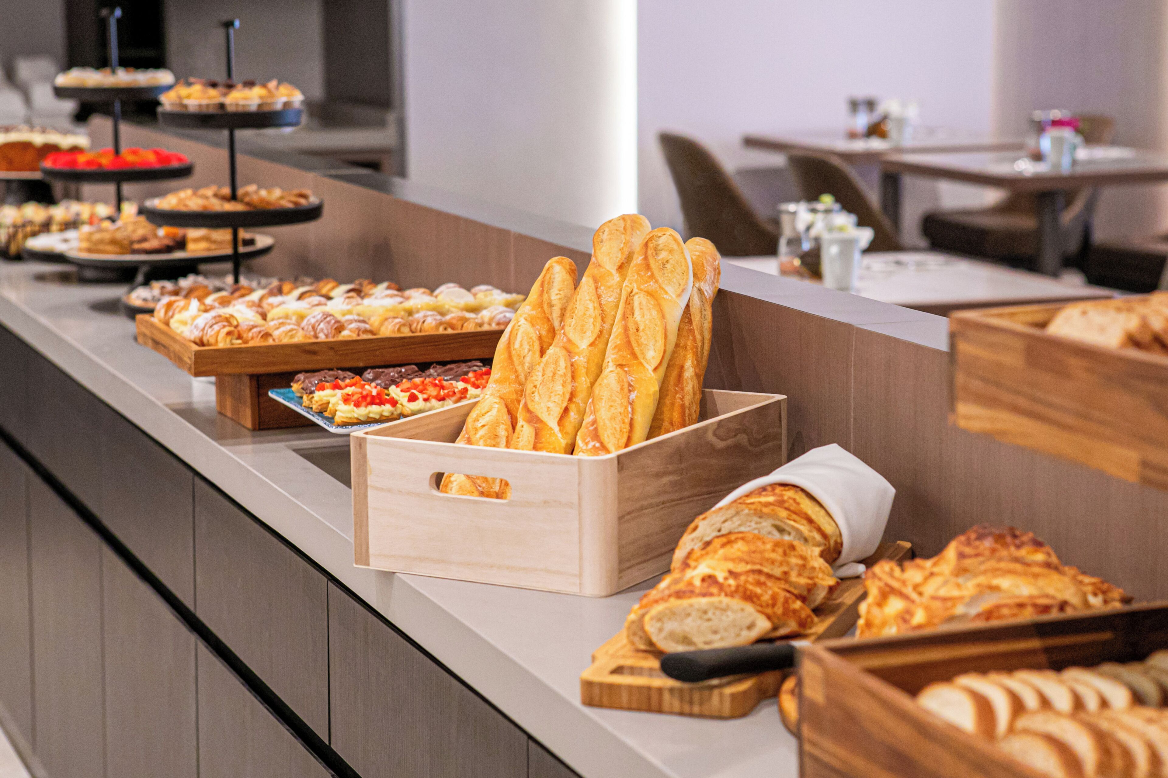 A buffet counter with various baked goods and pastries.