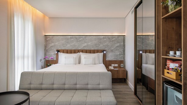 Une chambre d’hôtel moderne, dotée d’un grand lit, d’un canapé, d’une table de chevet et d’une armoire.