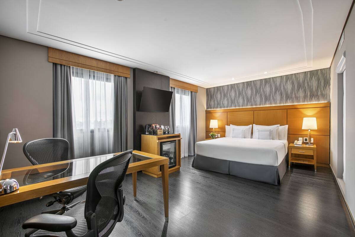 Ein Hotelzimmer mit Bett, Schreibtisch, Stuhl, Fernseher und einer Wand mit Muster.