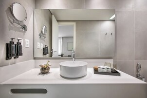 Un baño moderno con un lavabo redondo, un espejo grande y una pequeña planta en la encimera.