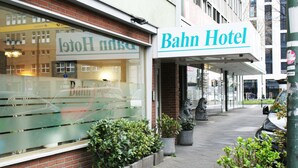 A Bahn Hotel with a visible entrance, potted plants, and a statue on the sidewalk. - Bahn Hotel (Düsseldorf)