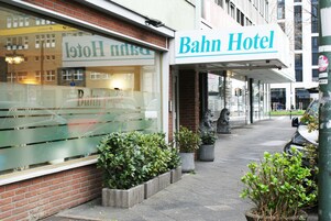 Un hotel Bahn con un ingresso ben visibile, piante in vaso e una statua sul marciapiede.
