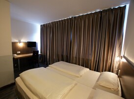 Una camera d'albergo con un letto, una scrivania, una sedia e un televisore.