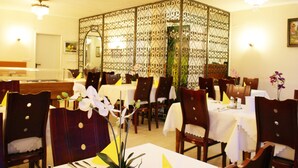 A dining area with wooden chairs and tables, a decorative partition, and a chandelier. - Bahn Hotel (Düsseldorf)