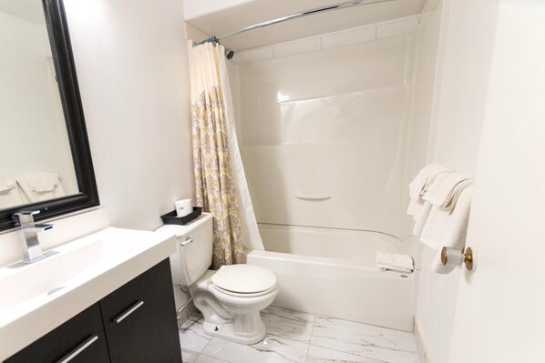A modern bathroom with a white sink, toilet, and bathtub.