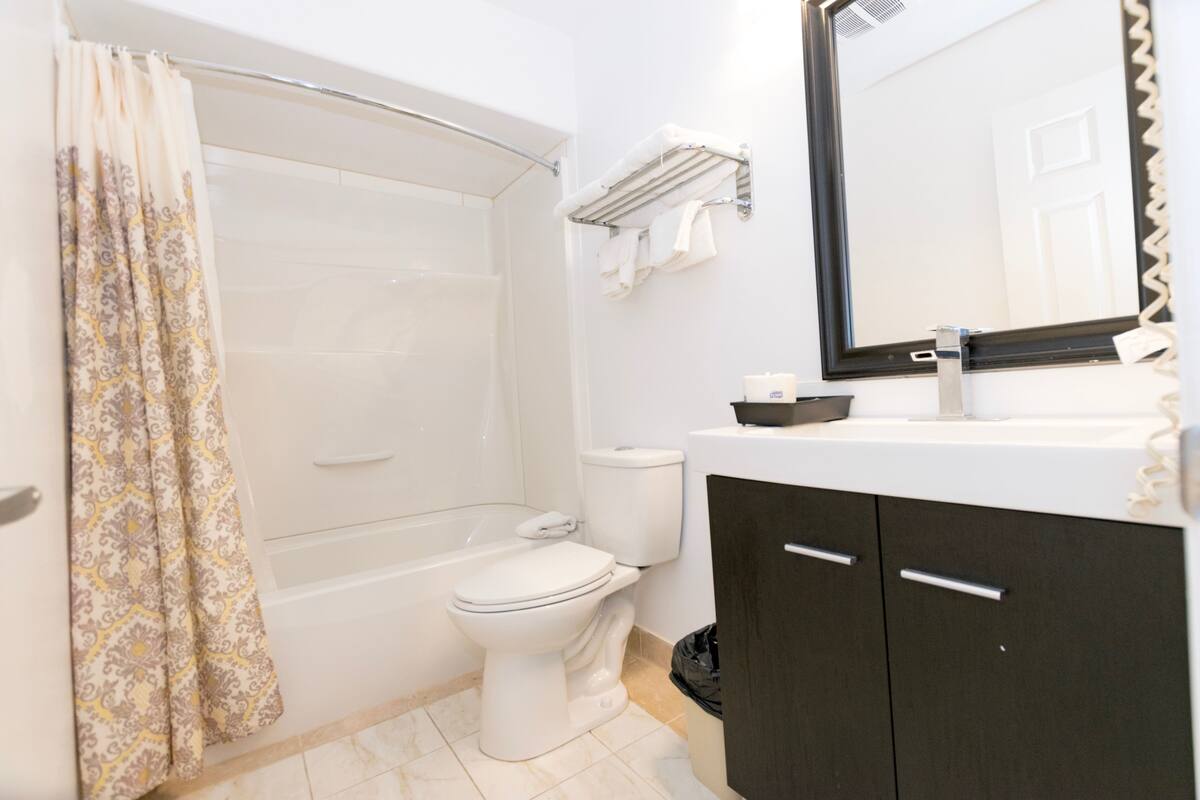 Un baño con bañera, inodoro y tocador con espejo.