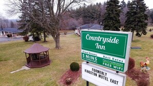 Señal de Countryside Inn, destacando características como a 5 minutos del centro, habitaciones excelentes, las mejores tarifas, unidades completamente amobladas y WiFi gratuito.