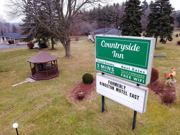 A sign for Countryside Inn, highlighting features like 5 mins to downtown, great rooms, best rates, fully furnished units, and free WiFi. - Countryside Inn (Kingston)