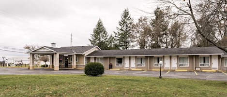 A motel with a covered front area, multiple rooms, and a parking lot.
