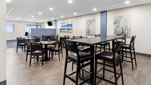 A conference room with a long table and chairs, large windows, and artwork on the walls.