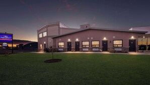 A modern building with a flat roof, multiple windows, and a well-maintained lawn.
