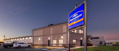 A Howard Johnson's by Wyndham hotel with a modern facade, parking lot, and well-lit exterior.
