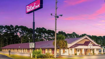 A Red Roof Inn with a two-story building, a parking lot, and a clear sky.