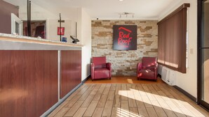 A reception area with a stone wall, two leather chairs, a reception desk, and a sign reading "Red Roof Inn". - Red Roof Inn Santee (Santee)