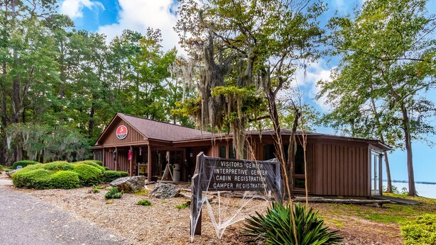 A cabin with a sign indicating it is a visitors center, interpretive center, cabin registration, and camper registration. - Red Roof Inn Santee (Santee)