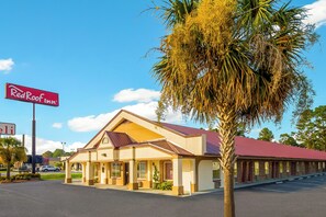 A Red Roof Inn with a single-story structure, a red roof, and a palm tree in front.