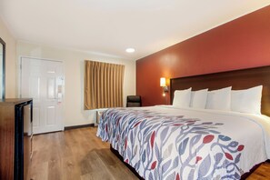 A hotel room with a bed, a desk, a chair, a door, and a window with curtains. - Red Roof Inn Santee (Santee)
