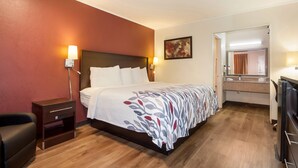 A hotel room with a bed, bedside tables, a desk, and a mirror. - Red Roof Inn Santee (Santee)