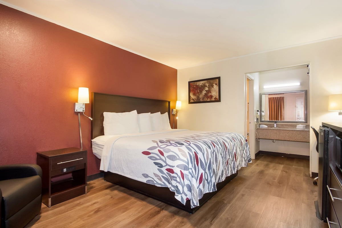 Ein Hotelzimmer mit Bett, Nachttischen, einem Schreibtisch und einem Spiegel.