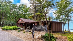 A cabin with a sign indicating it is a visitors center, interpretive center, cabin registration, and camper registration. - Red Roof Inn Santee (Santee)
