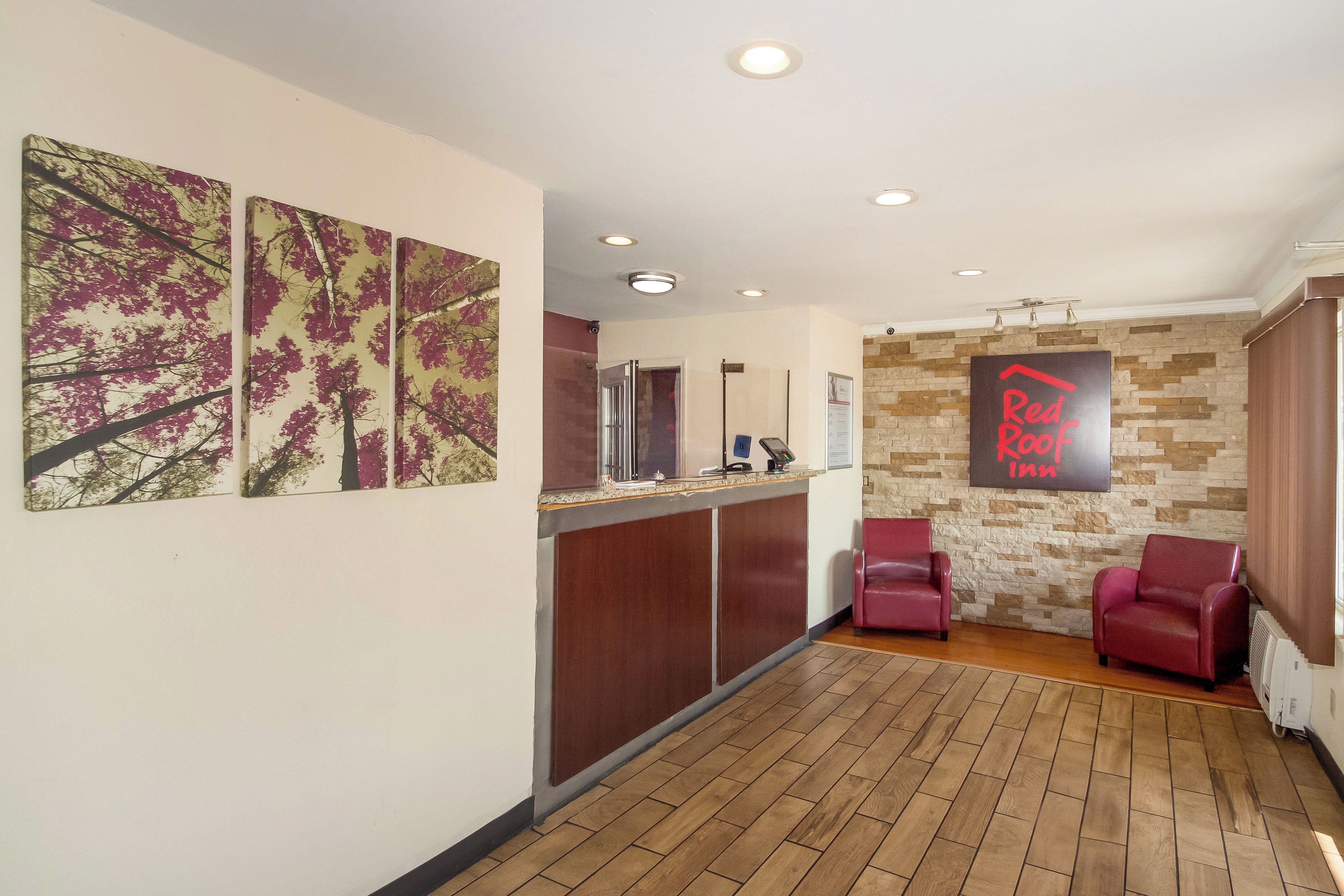A reception area with a wooden floor, a reception desk, and two red leather chairs.