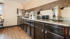 A kitchen with dark wooden cabinets, a granite countertop, and a coffee maker. - Red Roof Inn Santee (Santee)