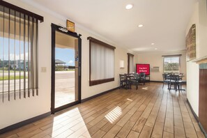 A hotel lobby with a reception desk, a dining area with tables and chairs, and a view of the outside. - Red Roof Inn Santee (Santee)