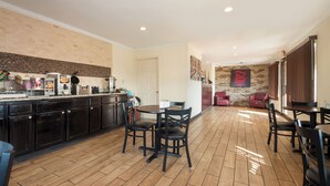 Una cocina amplia con comedor, que incluye una encimera con diversos electrodomésticos y un conjunto de mesas y sillas.