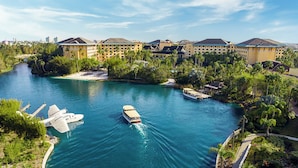 A river with boats, a dock, and a large hotel with multiple buildings. - Universal’s Loews Royal Pacific Resort (Orlando)