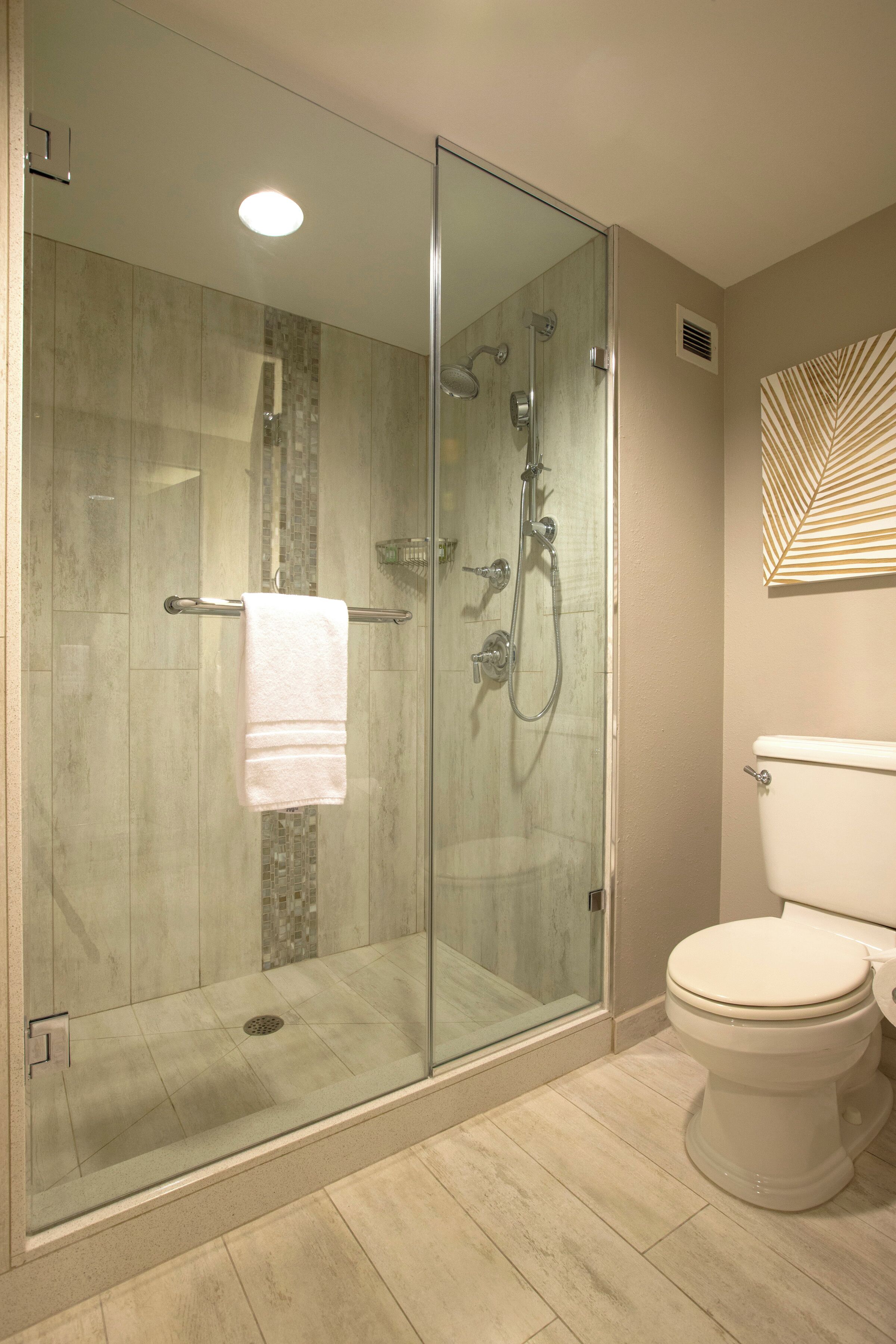 Een moderne badkamer met een douchecabine van glas, een toilet en een decoratief wandobject.