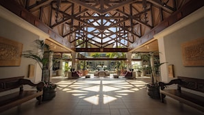A spacious lobby with a high wooden ceiling, large potted plants, and comfortable seating areas. - Universal’s Loews Royal Pacific Resort (Orlando)