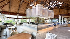 A spacious indoor area with a high ceiling, a bar area with a counter and seating, and a view of greenery outside. - Universal’s Loews Royal Pacific Resort (Orlando)