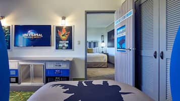 A hotel room with a bed, a desk, and a TV displaying the Universal Orlando Resort logo.