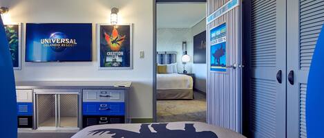 Een hotelkamer met een bed, een bureau en een televisie waarop het logo van Universal Orlando Resort staat.