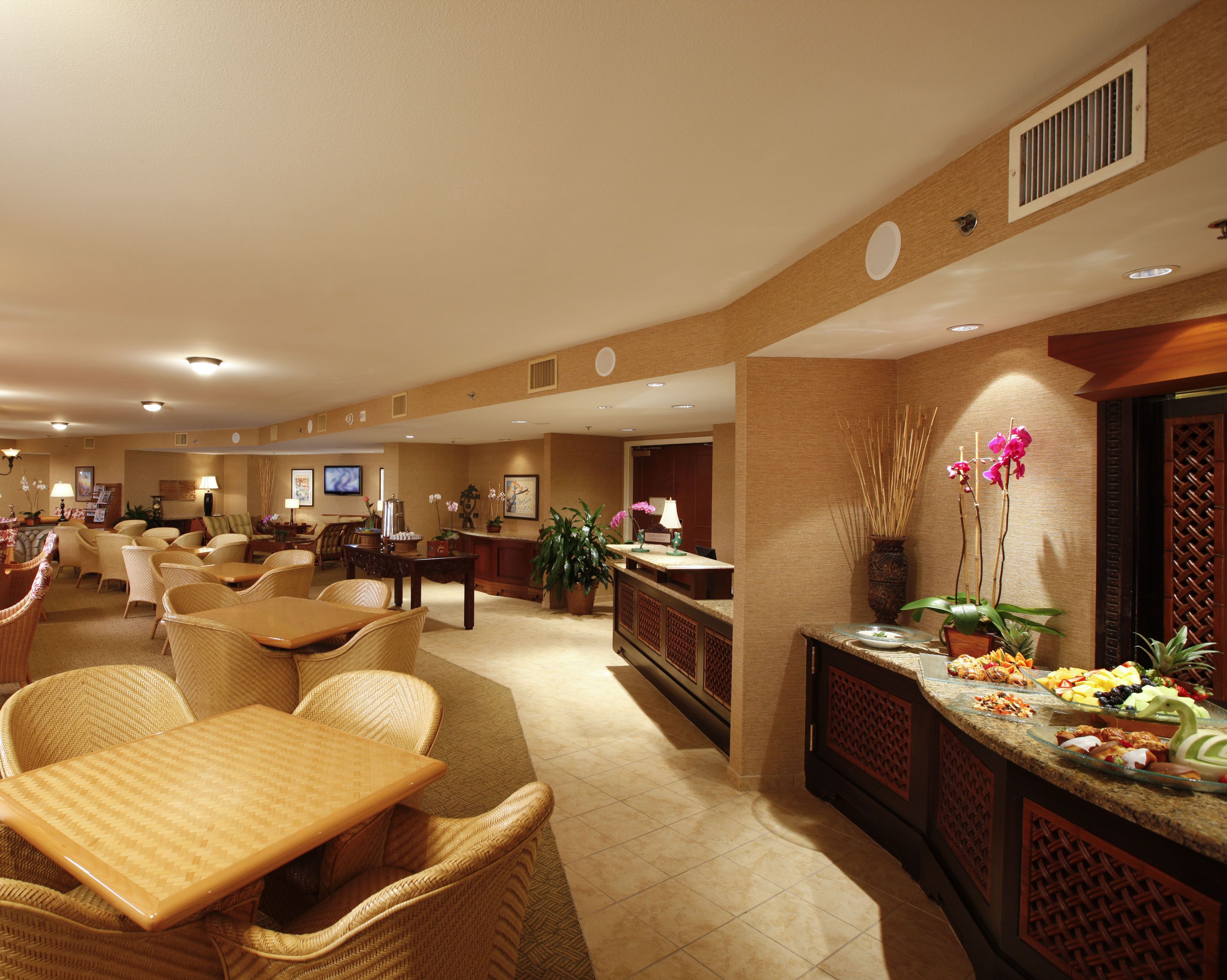 A spacious hotel lobby with a reception desk, seating area, and a television.