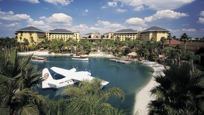 A resort with a large pool, a boat, and a jet in the water. - Universal’s Loews Royal Pacific Resort (Orlando)